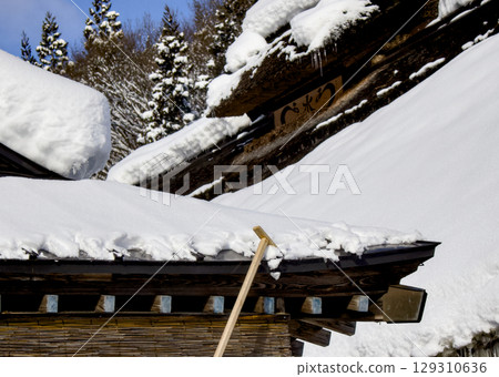 A scene of workers removing snow from the roof using a snow shovel 129310636