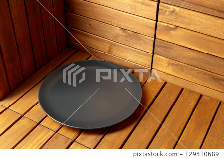 Empty black plate on natural wooden background. Empty black plate on natural wooden background. 129310689