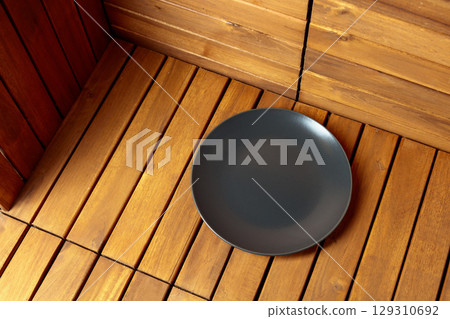 Empty black plate on natural wooden background. 129310692