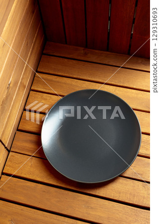 Empty black plate on natural wooden background. 129310693