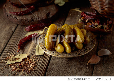Pickled cucumbers with ingredients on an old wooden table. Pickled cucumbers with ingredients on an old wooden table. 129310724