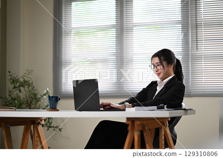 Professional businesswoman working on a laptop at a modern desk 129310806