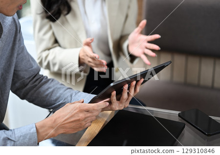 Close up of colleagues working together on laptop, reviewing documents and business data 129310846