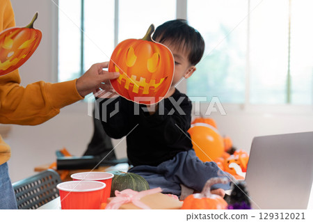 Halloween Fun. Child and adult preparing festive decorations with pumpkin masks. 129312021