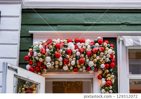 Festive Christmas garland with colorful ornaments and lights hanging over doorway Festive Christmas garland with colorful ornaments and lights hanging over doorway 129312072