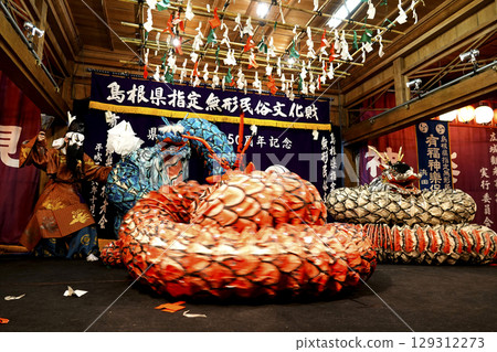 石見神樂(夜神樂)表演者和一條巨蛇在神社的禮拜殿舞台上跳舞 石見神樂(夜神樂)表演者和一條巨蛇在神社的禮拜殿舞台上跳舞 129312273