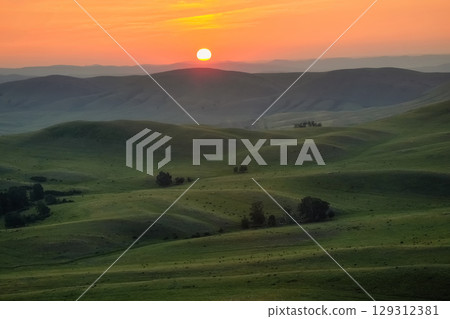 Sun rises over a picturesque mountain valley 129312381
