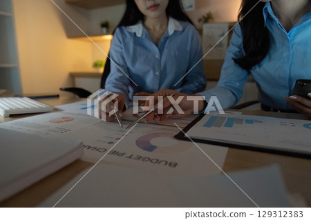 Team Analysis. Close-up of two professionals reviewing budget charts and data in a collaborative workspace. Team Analysis. Close-up of two professionals reviewing budget charts and data in a collaborative workspace. 129312383