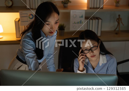 Focused Collaboration. Women discussing project details in a modern workspace. Focused Collaboration. Women discussing project details in a modern workspace. 129312385