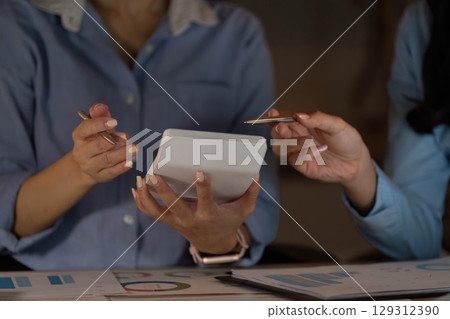 Collaborative Discussion. Two women reviewing data together in a modern office. 129312390