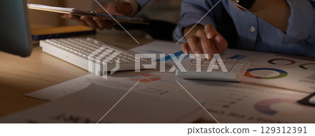 Accounting. Professional calculating financial data with a calculator and reports. 129312391