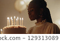 Young African American woman blowing out candles on birthday cake at home celebration 129313089