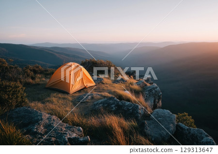 Golden Camping Tent at Sunrise Overlooking Serene Mountain Valley 129313647