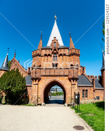 Entrance gate and stone walls of Hradec nad Moravici Castle in the Czech Republic, showcasing Gothic revival architecture surrounded by greenery in a peaceful historic setting. 129314327