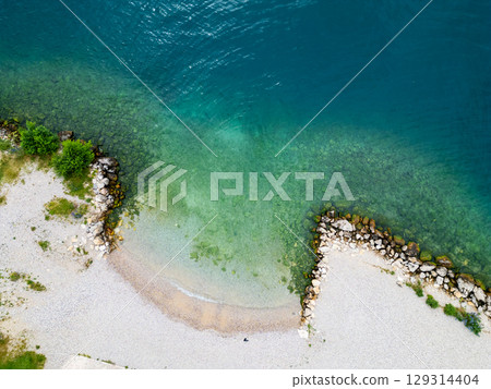Aerial drone view of Lago di Garda (lake Garda) coastline, Italy. The beach and fresh blue water. Aerial drone view of Lago di Garda (lake Garda) coastline, Italy. The beach and fresh blue water. 129314404