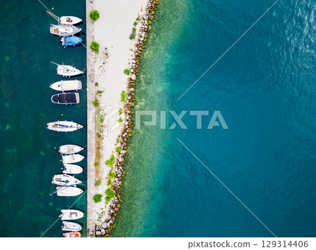 Aerial drone view of Lago di Garda (lake Garda) coastline, Italy. The beach and fresh blue water. Aerial drone view of Lago di Garda (lake Garda) coastline, Italy. The beach and fresh blue water. 129314406