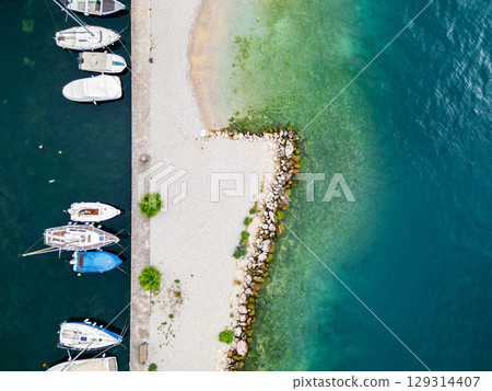 Aerial drone view of Lago di Garda (lake Garda) coastline, Italy. The beach and fresh blue water. Aerial drone view of Lago di Garda (lake Garda) coastline, Italy. The beach and fresh blue water. 129314407