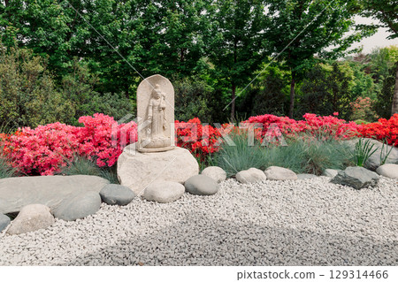 Japanese garden with stone statue, vibrant azaleas, and peaceful rock landscape in spring. Japanese garden with stone statue, vibrant azaleas, and peaceful rock landscape in spring. 129314466