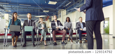 Man speaking on a business meeting in modern office in front of a group of company employees. 129314792