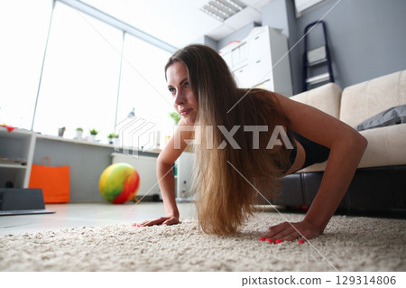 Workout session in a modern living room with a dedicated fitness enthusiast practicing push-ups on a cozy rug Workout session in a modern living room with a dedicated fitness enthusiast practicing push-ups on a cozy rug 129314806