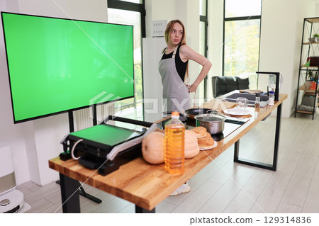 Cooking demonstration in a modern kitchen with a vibrant green screen and a charming chef preparing a delicious meal during the day 129314836
