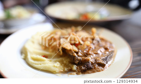 Deliciously plated dish with tender meat and creamy mashed potatoes garnished with crispy toppings Deliciously plated dish with tender meat and creamy mashed potatoes garnished with crispy toppings 129314934