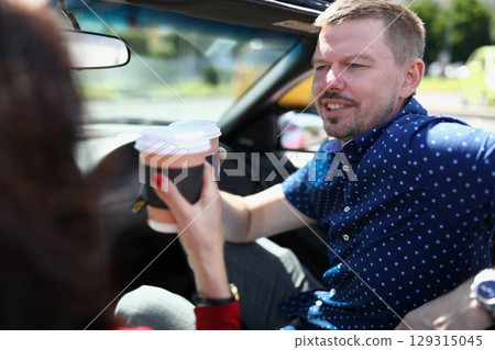 Enjoying a sunny morning drive with coffee and good conversation in a convertible car 129315045