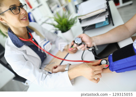 Health check-up with a medical professional examining a patient's blood pressure in a bright clinic setting 129315055