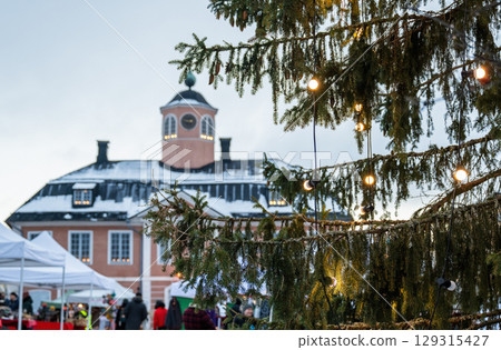 Christmas lights on tree branches with historical building in background at winter market 129315427