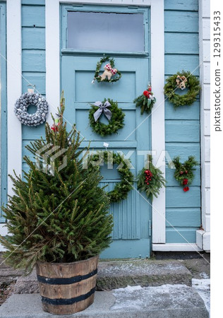 Handmade Christmas wreaths and decorations hanging on blue wooden door 129315433