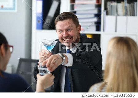 Exciting office celebration with a cheerful colleague sharing cocktails in a modern workspace during afternoon hours 129316520