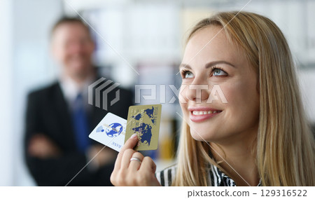 Woman holding credit cards while smiling in a modern office environment during a business meeting in daylight hours 129316522