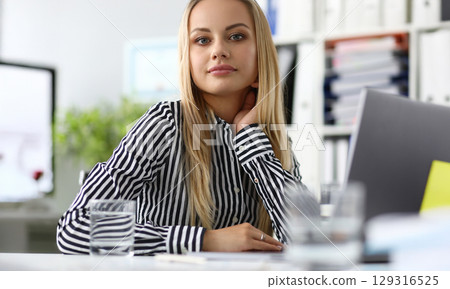 Young professional woman engaged in creative work at a modern office setting while contemplating ideas for her project 129316525