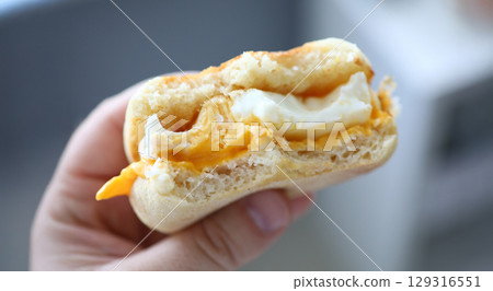 Delicious breakfast biscuit filled with creamy egg and melted cheese enjoyed in a cozy kitchen setting 129316551