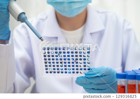 Scientist with cell culture in sample micro plate for research in science laboratory. 129316825