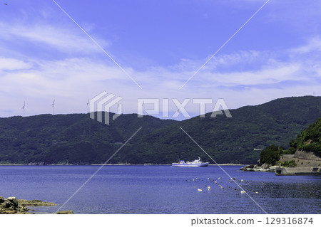 Summer scenery of windmills on the Sada Misaki Peninsula and a ferry floating on the sea in Ikata Town Summer scenery of windmills on the Sada Misaki Peninsula and a ferry floating on the sea in Ikata Town 129316874