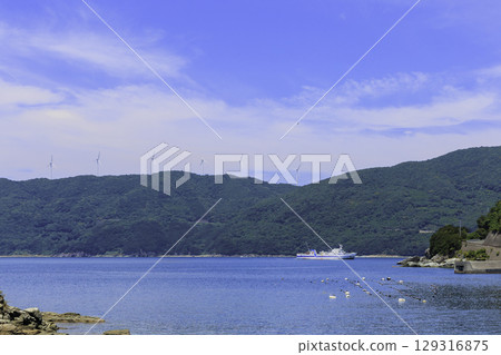 Summer scenery of windmills on the Sada Misaki Peninsula and a ferry floating on the sea in Ikata Town 129316875