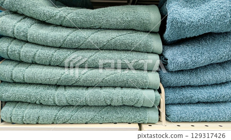 Several stacks of soft towels in shades of turquoise and teal, neatly folded and displayed on store shelf Several stacks of soft towels in shades of turquoise and teal, neatly folded and displayed on store shelf 129317426