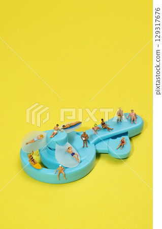 miniature people in swimsuits on a blue fan 129317676