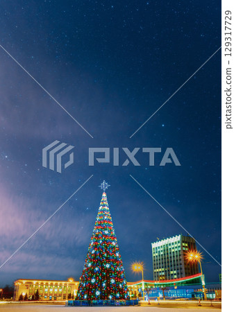 Glistening Christmas Tree Adorned with Lights Under Stars 129317729