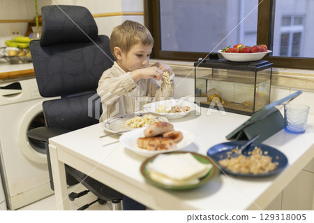 Child eating lunch at home with fish tank and tablet Child eating lunch at home with fish tank and tablet 129318005