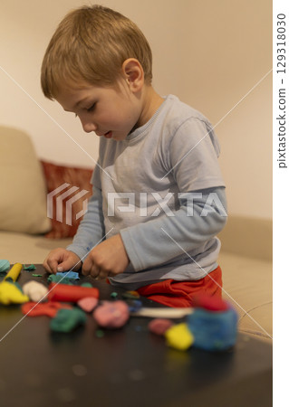 Young child playing with modeling clay at home 129318030