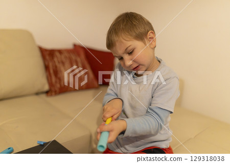 Child playing with connecting toys on sofa in living room 129318038