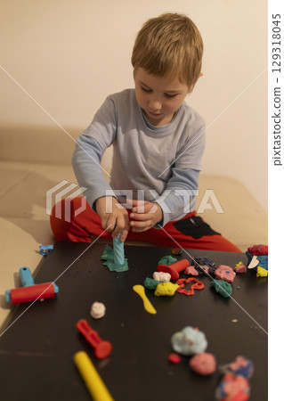 Child playing with modeling clay at home: developing creativity and fine motor skills 129318045