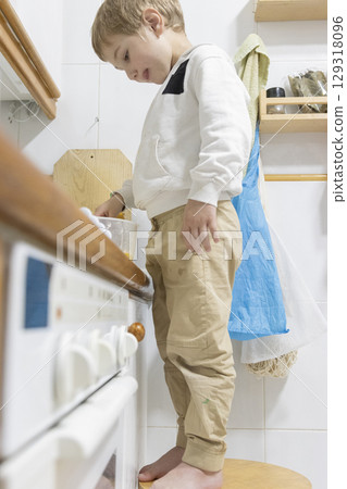 Curious child preparing food standing on stool in kitchen 129318096