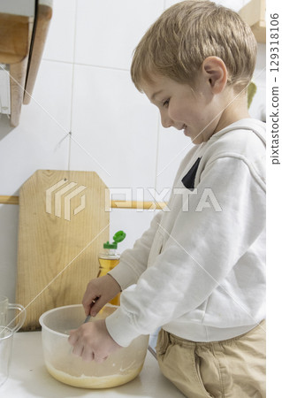 Happy child mixing ingredients in bowl, learning to cook 129318106