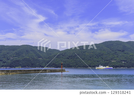 View of the port and ferry in Ikata Town with the windmills and red lighthouse of the Sada Misaki Peninsula View of the port and ferry in Ikata Town with the windmills and red lighthouse of the Sada Misaki Peninsula 129318241