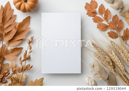 A blank card for Thanksgiving invitation mockup is centrally placed on a light surface, surrounded by various autumn decorations 129319044