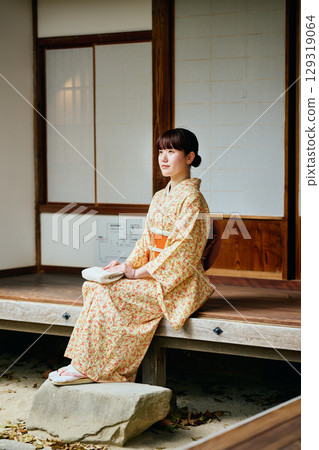 A woman in a kimono quietly standing on the veranda 129319064