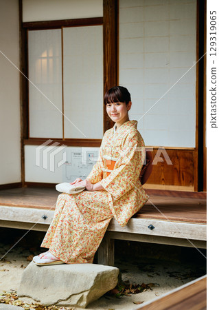 A woman in a kimono quietly standing on the veranda 129319065